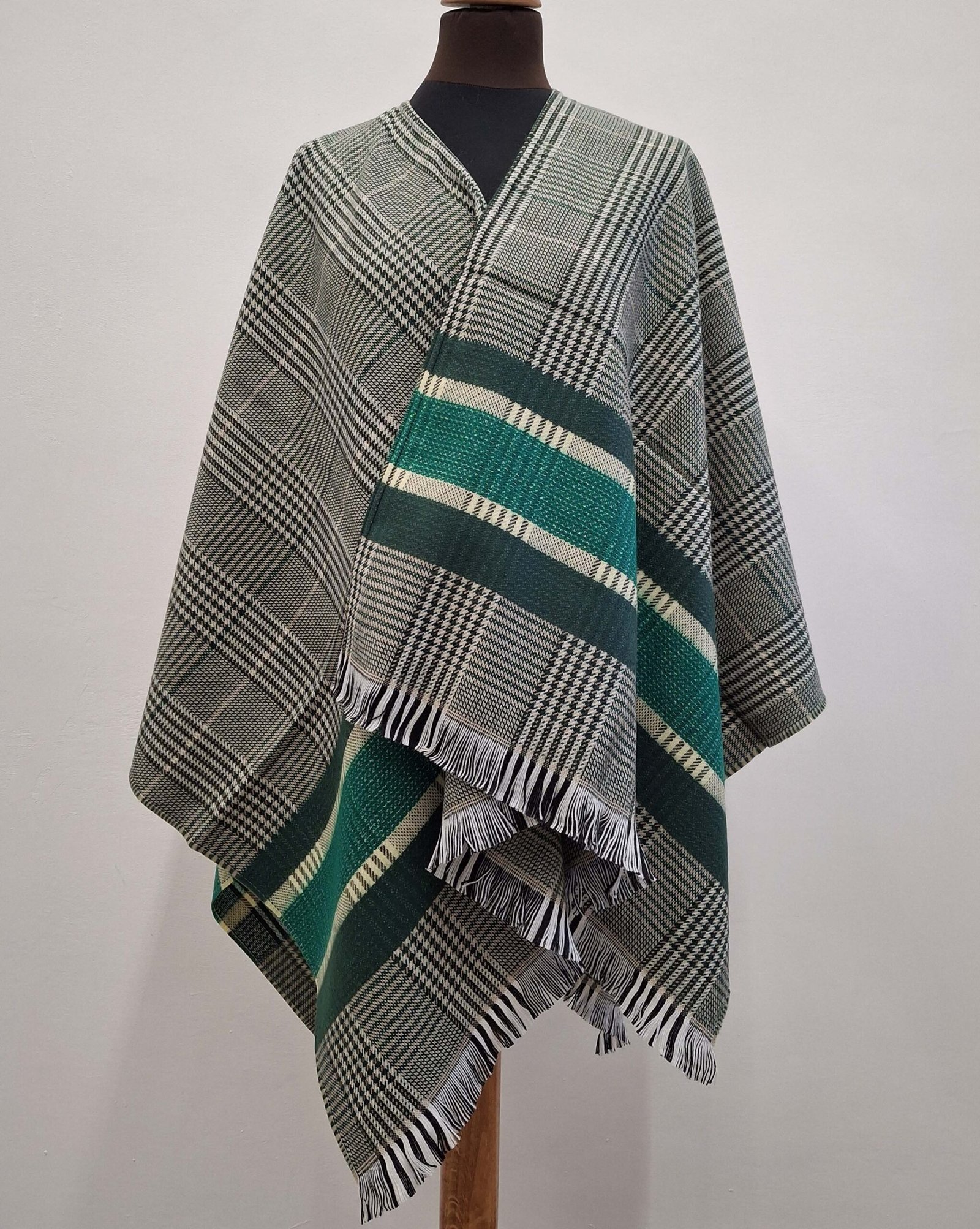Poncho gris à petits carreaux avec une bande verte élégante, idéal pour un style moderne et confortable.