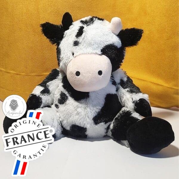 Bouillotte peluche vache assise chauffante, remplie de blé et de lavande, distribuée par Acaponcho, fabriquée en France pour une chaleur douce et réconfortante.